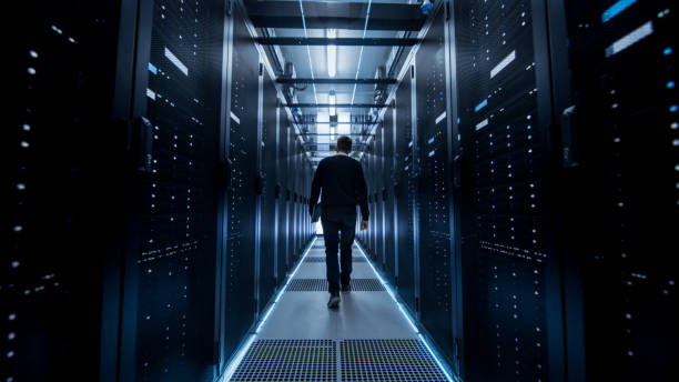 istock Following Shot of IT Engineer Walking Through Data Center Corridor with Rows of Rack Servers. 802303638