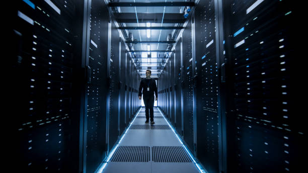 istock Shot of IT Engineer Walking Through Data Center Corridor with Rows of Rack Servers. 802303692