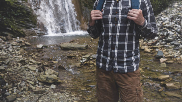 istock Hands Unrecognizable Man Holds Backpack Strap On Waterfall Background Hiking Journey Travel Trek Concept 802304406
