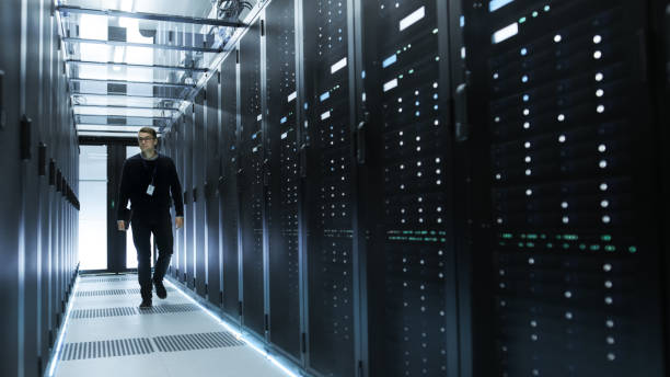istock IT Engineer Holding Notebook and Walking Through Data Center Full of Working Rack Servers. 802320806