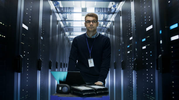 istock Shot of Server Engineer Pushing Crash Cart with Laptop, Hard Drives and Hardware Through Data Center. He Walks along Rows of Server Racks. 802320862