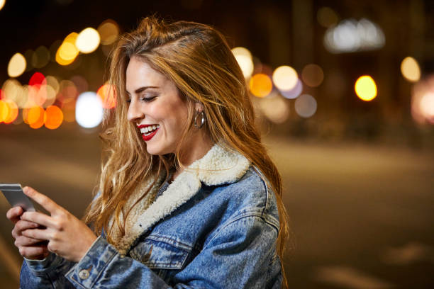 istock Cheerful woman using mobile phone in city at night 802321388