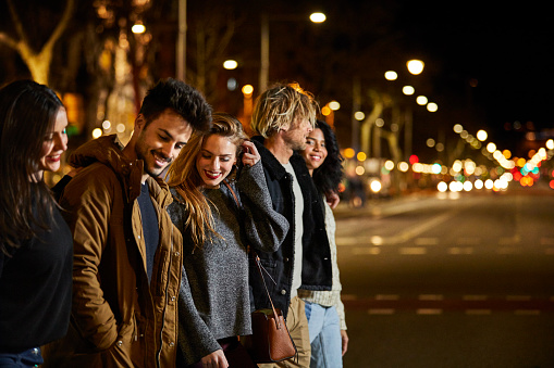 Multi-ethnic friends crossing city street at night