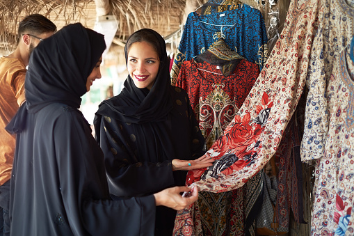 Middle eastern women checking out displayed dress