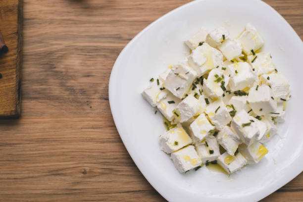 Feta cheese cubes and parsley on a wooden background stock photo