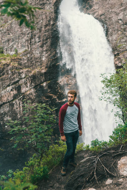 istock Man standing near the Manafossen waterfall in Norway 802345018