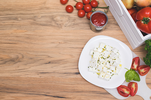 feta cheese cut in cubes, vegetables, herbs and olive oil-the ingredients for a greek salad