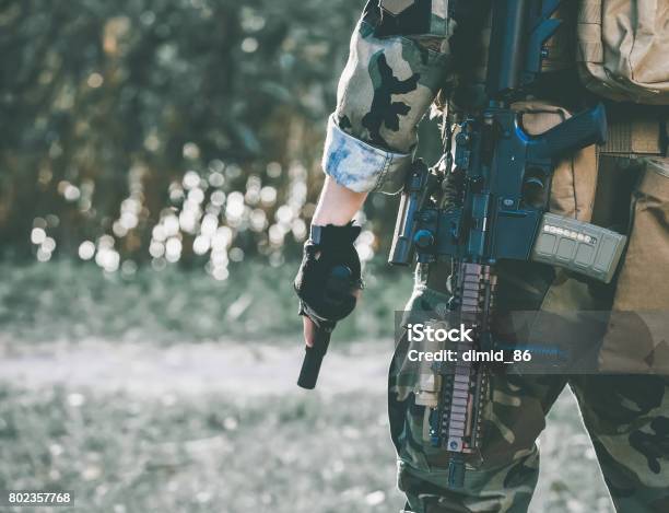 The Soldier In The Performance Of Tasks In Camouflage And Protective Gloves Holding A Gun Stock Photo - Download Image Now