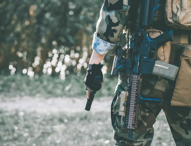 the soldier in the performance of tasks in camouflage and protective gloves holding a gun. - airsoft gun imagens e fotografias de stock