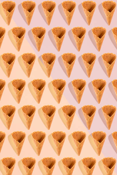 istock Sugar waffle cone for ice cream arranged in pattern on pink background. The image with copy space can be used as a background for the design of the confectionery menu 802378092