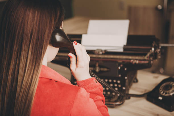 sekretarka w starej maszynie do pisania z telefonem. młoda kobieta za pomocą maszyny do pisania. koncepcje biznesowe. - author writing retro revival women zdjęcia i obrazy z banku zdjęć