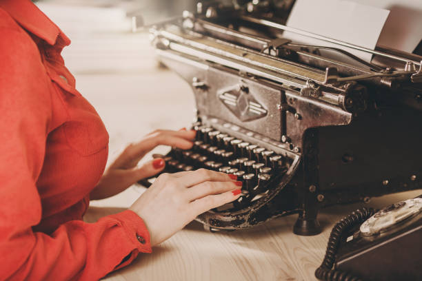 sekretärin am alten schreibmaschine mit telefon. junge frau mit schreibmaschine. business-konzepte. - author writing retro revival women stock-fotos und bilder