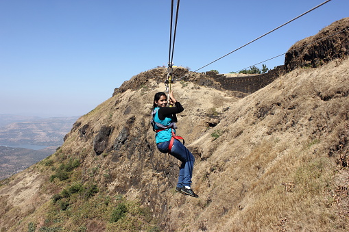 A young girl enjoying valley crossing at Singahad fort hill top near Pune in MAharashtra, India.