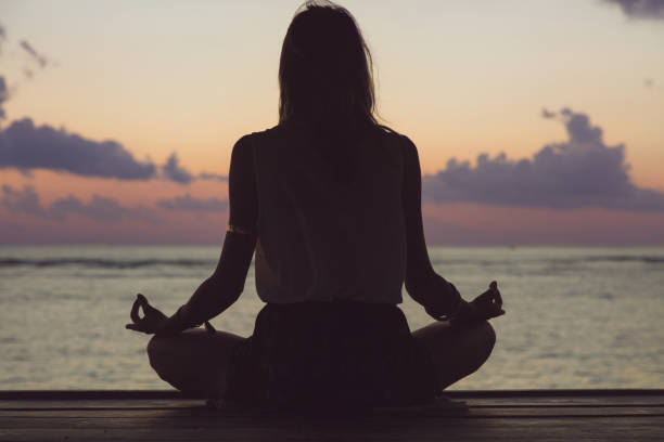 istock Woman practicing yoga on the beach. 802395564