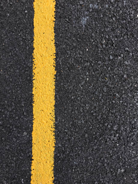 istock Yellow paint line on black asphalt road surface texture. space transportation background 802402638