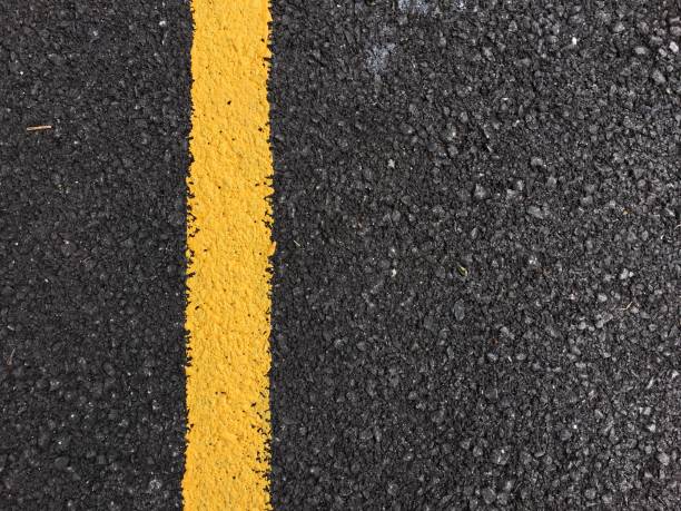 istock Yellow paint line on black asphalt road surface texture. space transportation background 802402738
