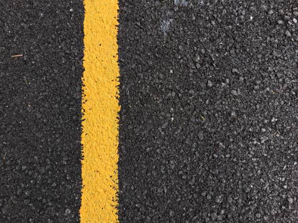 istock Yellow paint line on black asphalt road surface texture. space transportation background 802402972