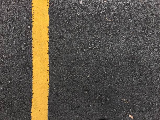 istock Yellow paint line on black asphalt road surface texture. space transportation background 802403414