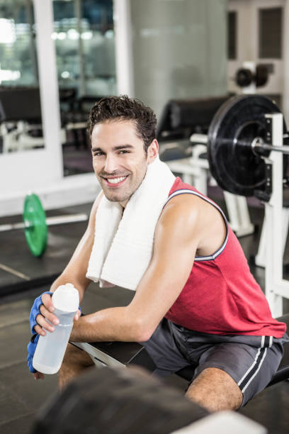 istock Smiling man sitting on bench and holding bottle of water 802421538