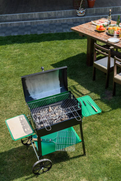 istock High angle view of grill with coals standing on green grass 802425600