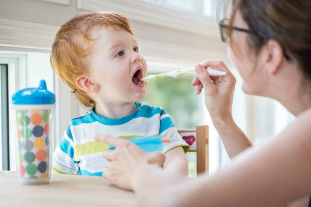istock Mother Feeding Baby Boy with Yogurt 802428296