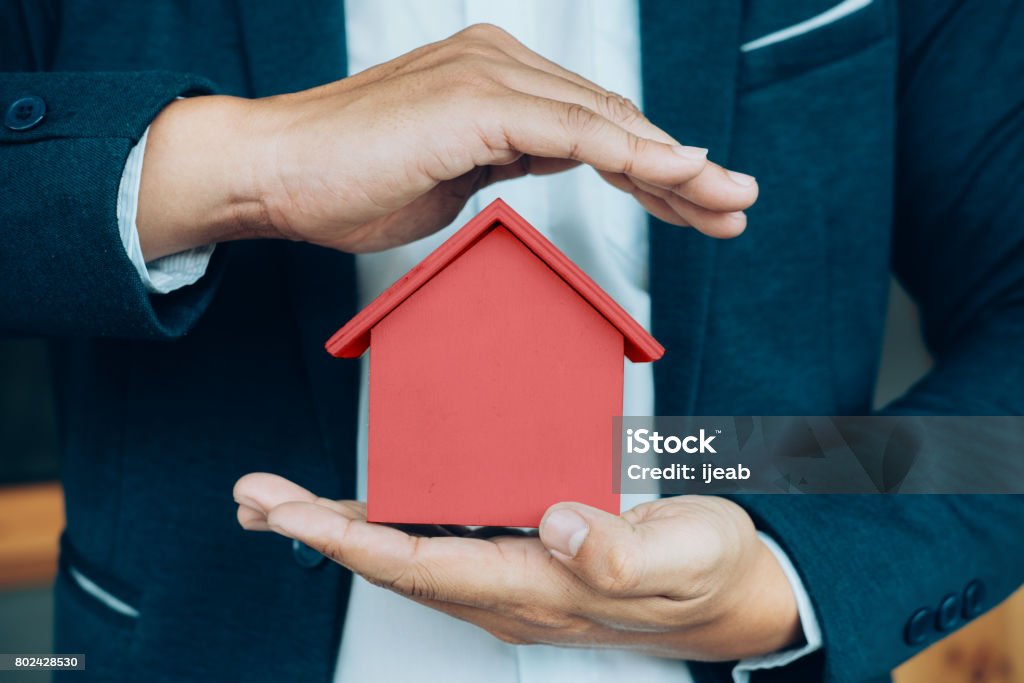 Business man hand hold the house model  saving small house. Business man hand hold the house model  saving small house. House insurance Domestic Life Stock Photo