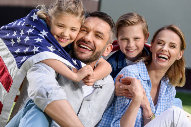 istock Happy family with american flag hugging outdoors, Independence Day concept 802429244