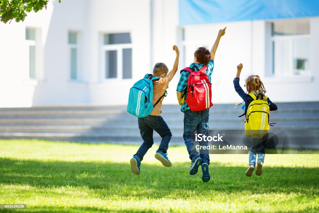Kinder mit Rucksäcken springen im Park in der Nähe von Schule - Lizenzfrei Bildung Stock-Foto