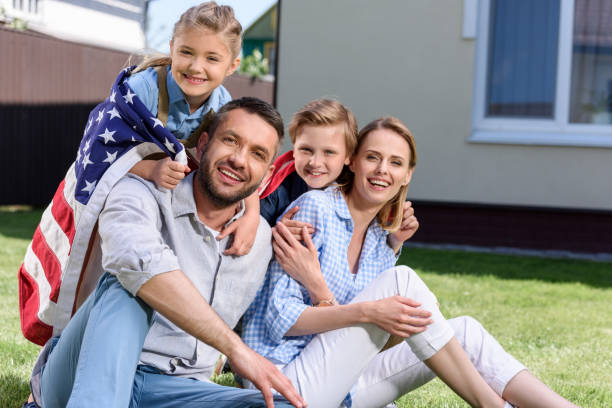 istock Happy family with american flag hugging outdoors, Independence Day concept 802429420