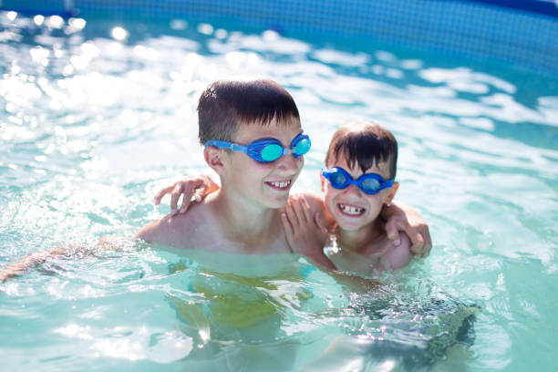 istock Happy little kids playing in swimming pool at summer 802429692