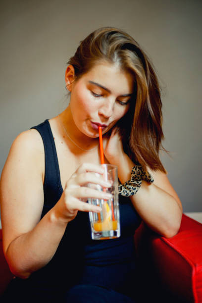 istock Happy young woman drinking juice in a cafe 802431956