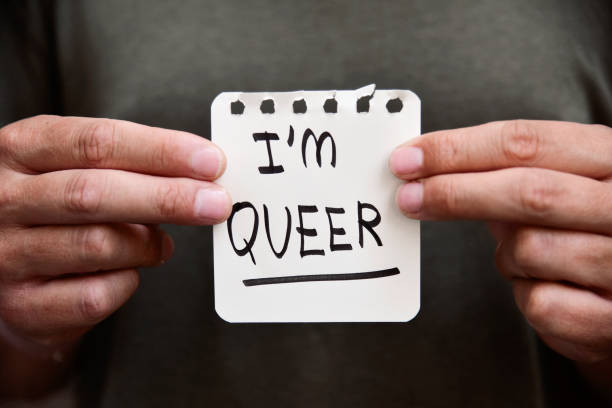 istock young man with a note with the text I am queer 802439906