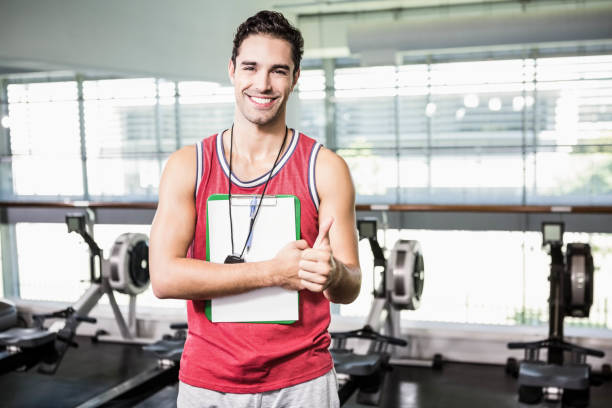 istock Smiling man standing with clipboard and stopwatch and showing thumb up 802443282