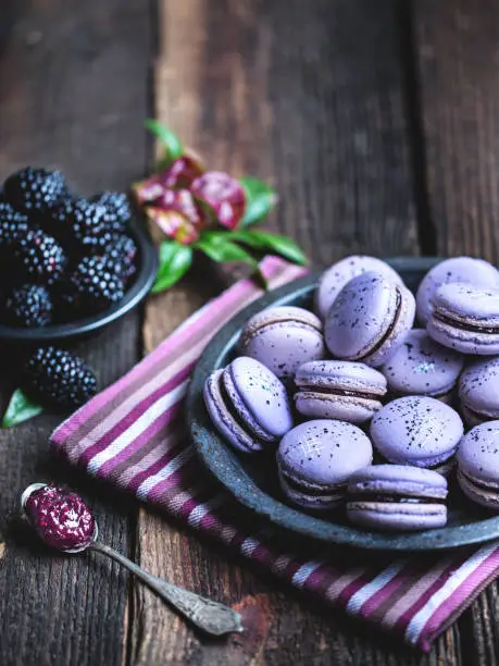 Photo of Blackberry macarons on a rustic wooden table.