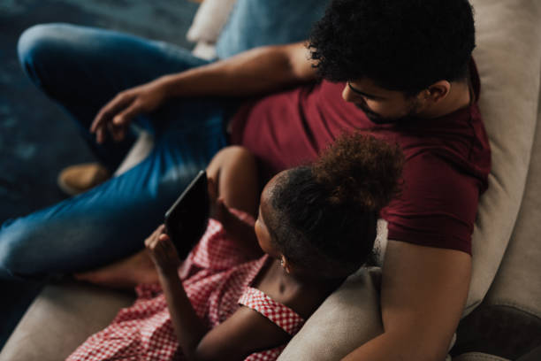 istock Father hugs his daughter while she's holding digital tablet 802448666