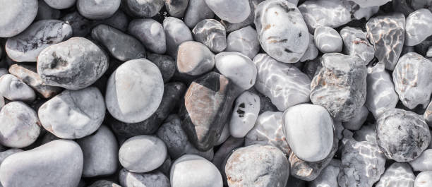 istock Sea pebbles on the beach under a layer of transparent water 802452416