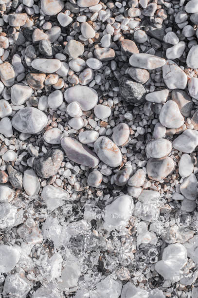 istock Sea pebbles on the beach under a layer of transparent water 802458908