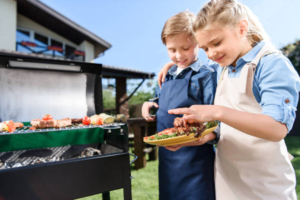 istock adorable children testing fresh meat just cooked on barbecue grill outdoors 802459018