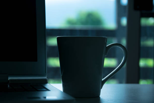 istock Close up drink cup and laptop on desk in home at morning time 802459566
