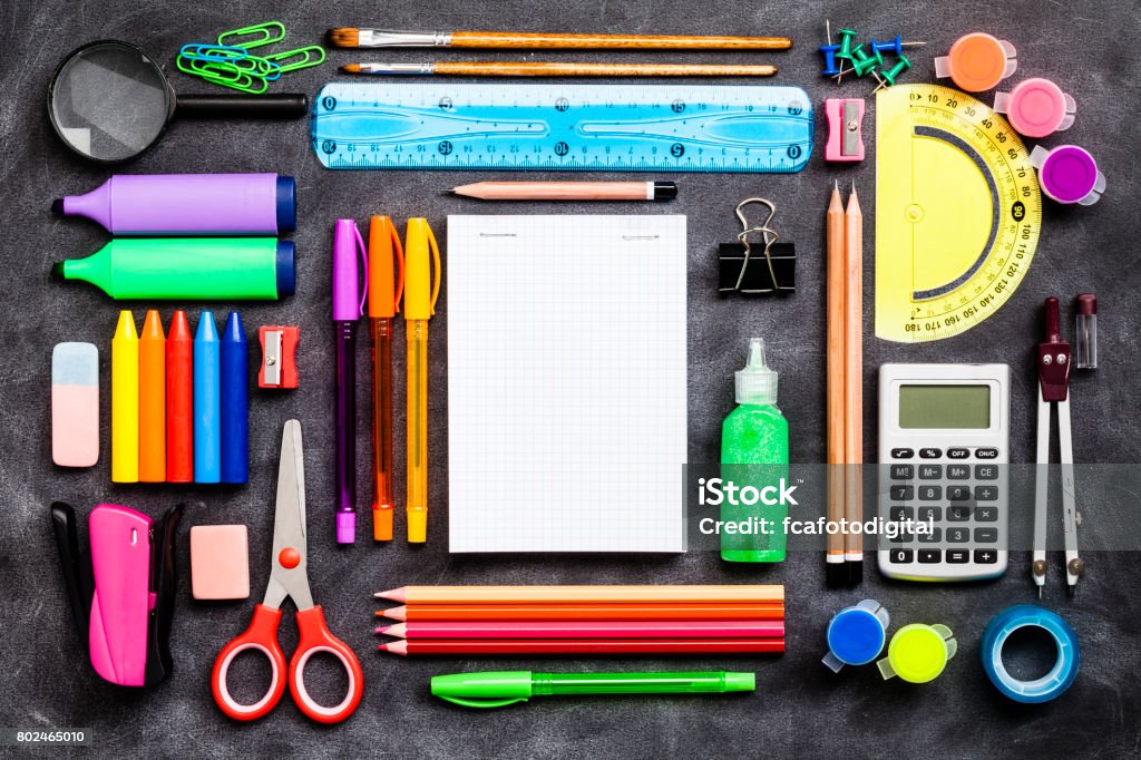 Top view of a large group of school or office supplies on black background Top view of a large group of multi colored school or office supplies shot on rustic black background. A blank note pad is at the center of the composition with a useful copy space ready for text and/or logo. DSRL studio photo taken with Canon EOS 5D Mk II and Canon EF 100mm f/2.8L Macro IS USM School Supplies Stock Photo