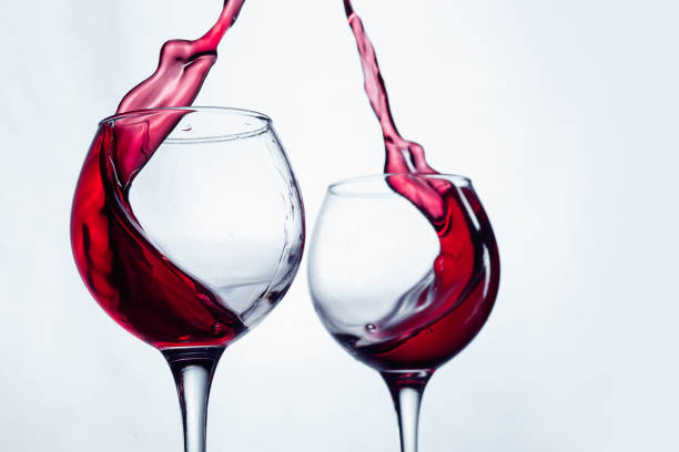 istock Two wine glasses in toasting gesture with big splashing 802472530