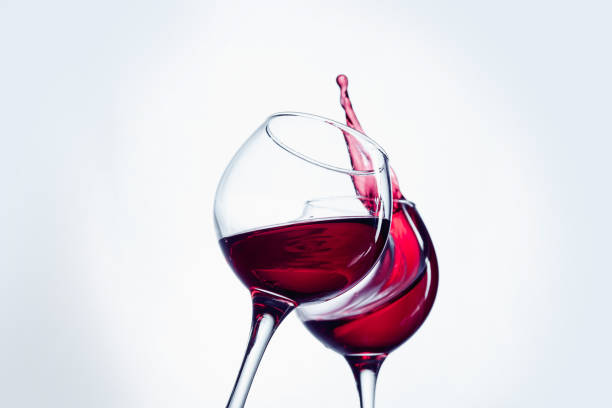 istock Two wine glasses in toasting gesture with big splashing 802472646