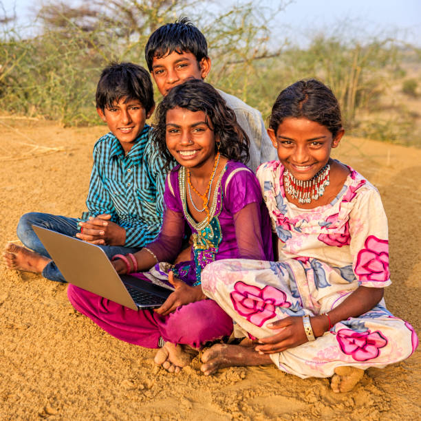 istock Happy Indian children using laptop, desert village, India 802472686