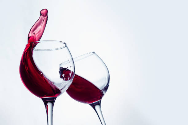 istock Two wine glasses in toasting gesture with big splashing 802472880