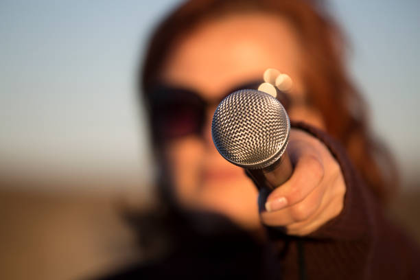 Woman holds microphone out towards camera Woman holds microphone out towards camera human cardiopulmonary system audio stock pictures, royalty-free photos & images