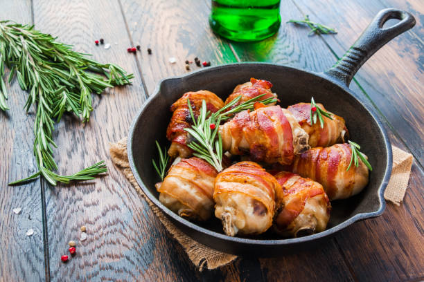 istock Bacon wrapped chicken drumsticks in a black cast-iron skillet on the wooden rustic table. 802476800