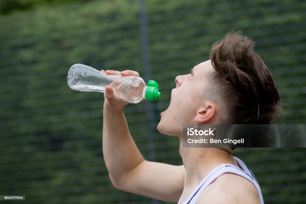 Teenage Boy Squirting Water Into His Mouth Stock Photo - Download Image Now  - Adolescence, Bottle, Drink - iStock