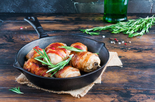 istock Bacon wrapped chicken drumsticks in a black cast-iron skillet on the wooden rustic table 802477250