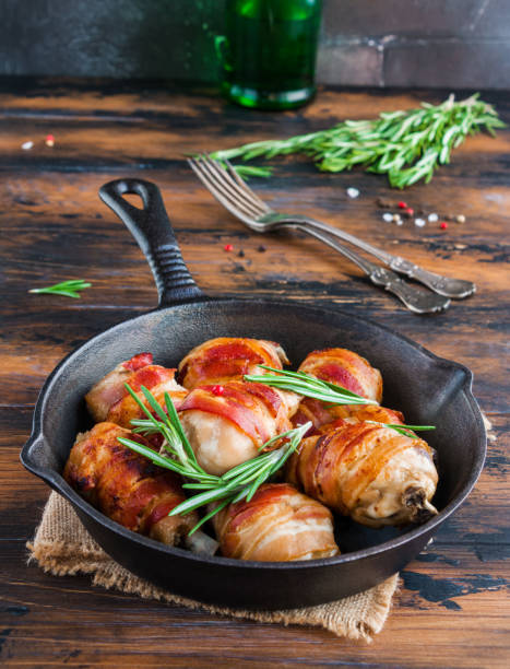istock Oven roasted bacon wrapped chicken drumsticks in a black baking pan on the wooden rustic table 802477664