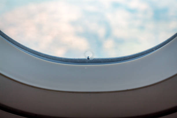 istock Airplane window breather hole bleed hole with wing blue sky 802480260
